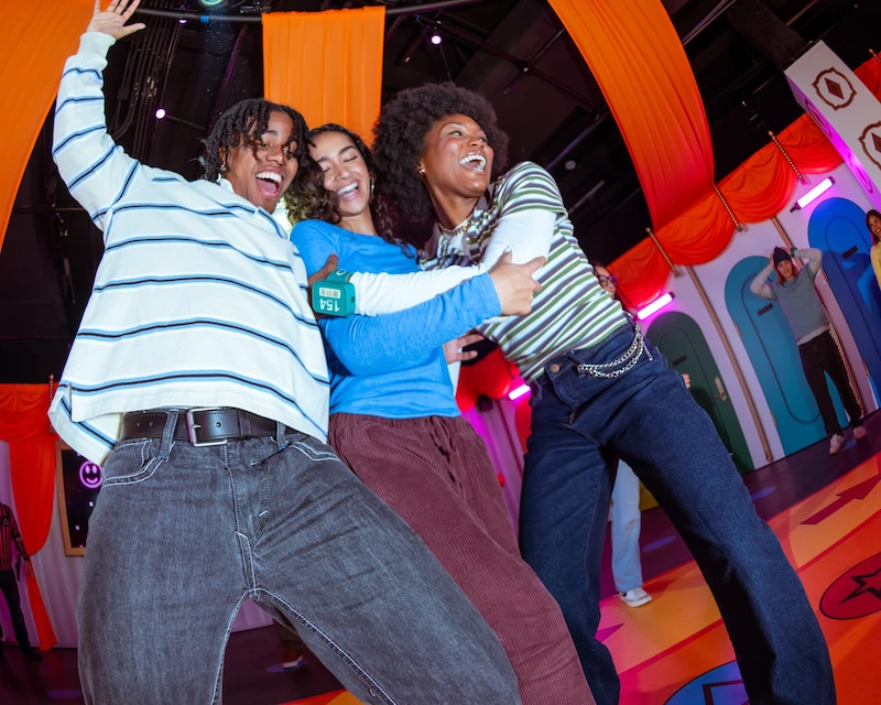 Three friends laugh in the Squid Game immersive experience.