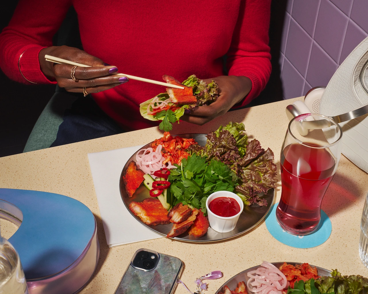 Woman enjoys pork ssam with sliced pork, korean spices, dipping sauces