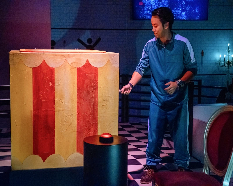 A man dressed in Squid Game garb plays an interactive game at the Squid Game experience.