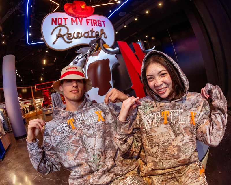 Two friends pose with their Dallas-themed Netflix hoodies.