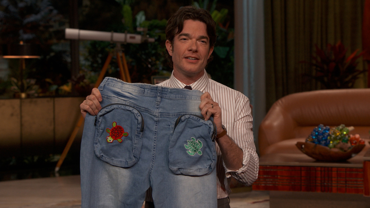 John Mulaney holds up a pair of jeans.