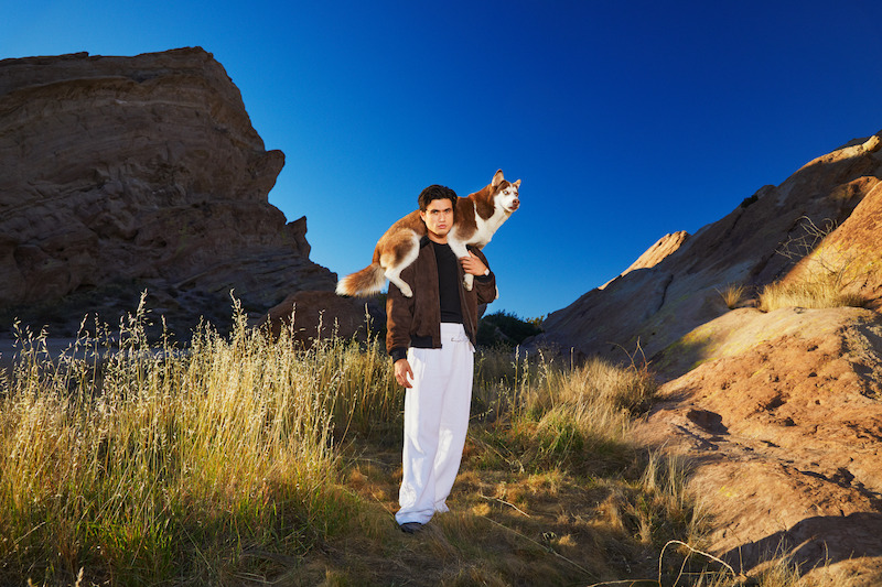 Charles Melton stands in the center of the frame.