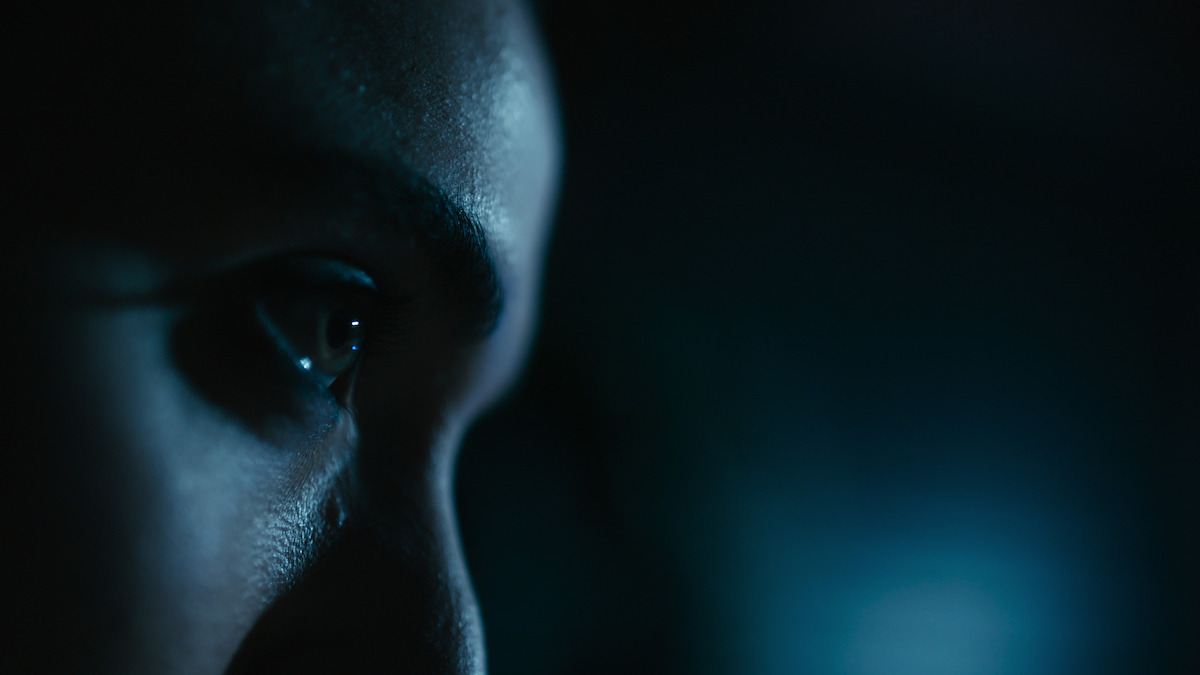 A woman stares off into the darkness.