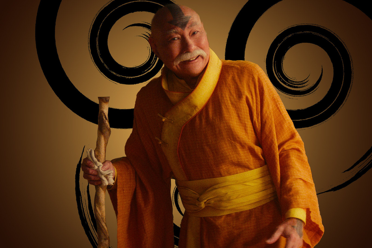 Lim Kay Siu as Gyatso wears orange Air Nomad robes and smiles in season 1 of ‘Avatar: The Last Airbender’
