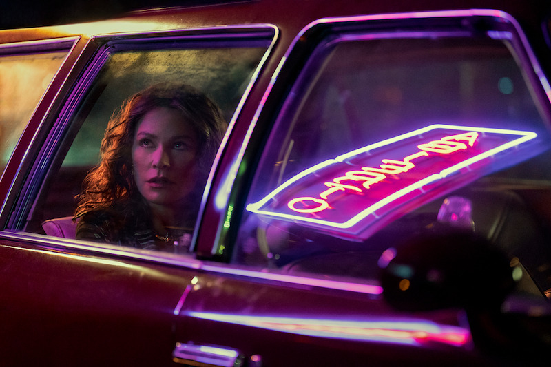 Sofia Vergara as Griselda in a car, neon sign reflecting off the window