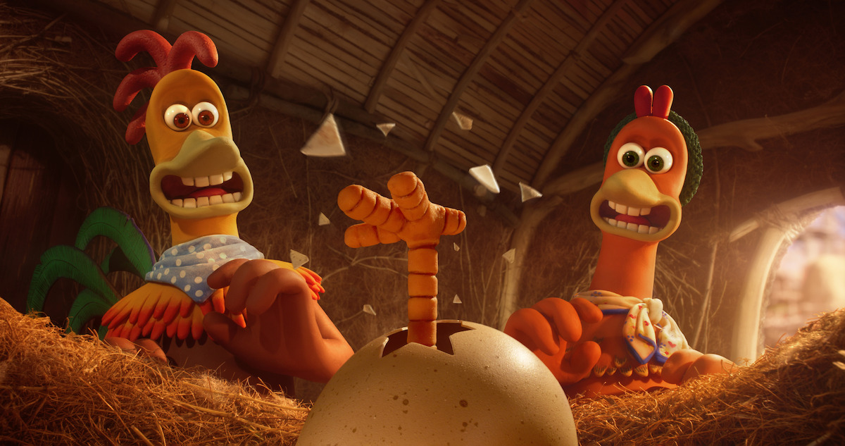 A rooster and chicken are surprised to see a leg pop out of an egg in ‘Chicken Run: Dawn of the Nugget’