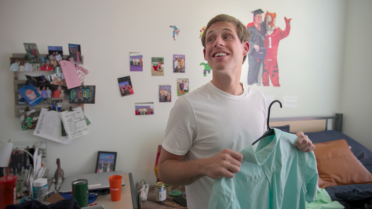 Tanner holding a shirt in his room.