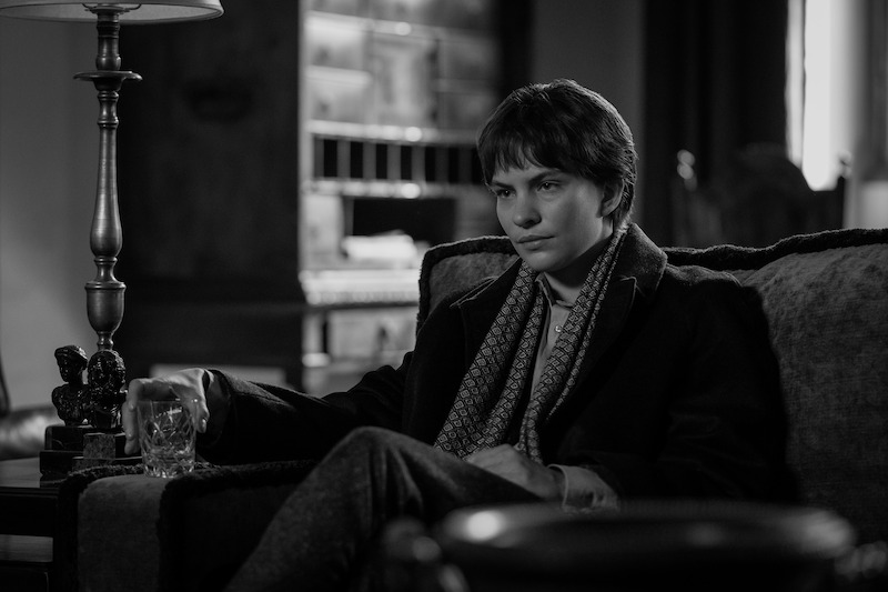 Eliot Sumner as Freddie Miles sits on a sofa in 'Ripley'