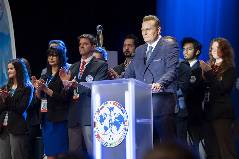 Carsten Norgaard as Gunther Braun speaks at a podium in Season 6, Part 2 of 'Cobra Kai'