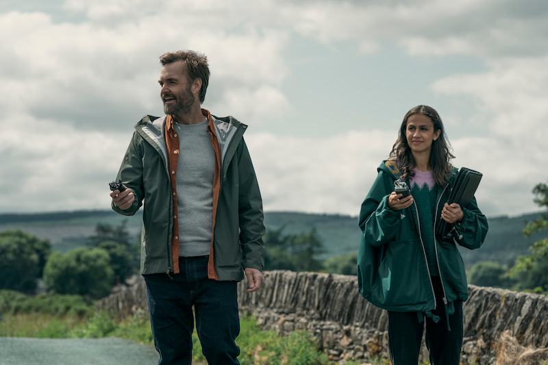Will Forte as Gilbert Power, and Robyn Cara as Emmy Sizergh stand in the Irish countryside in 'Bodkin'