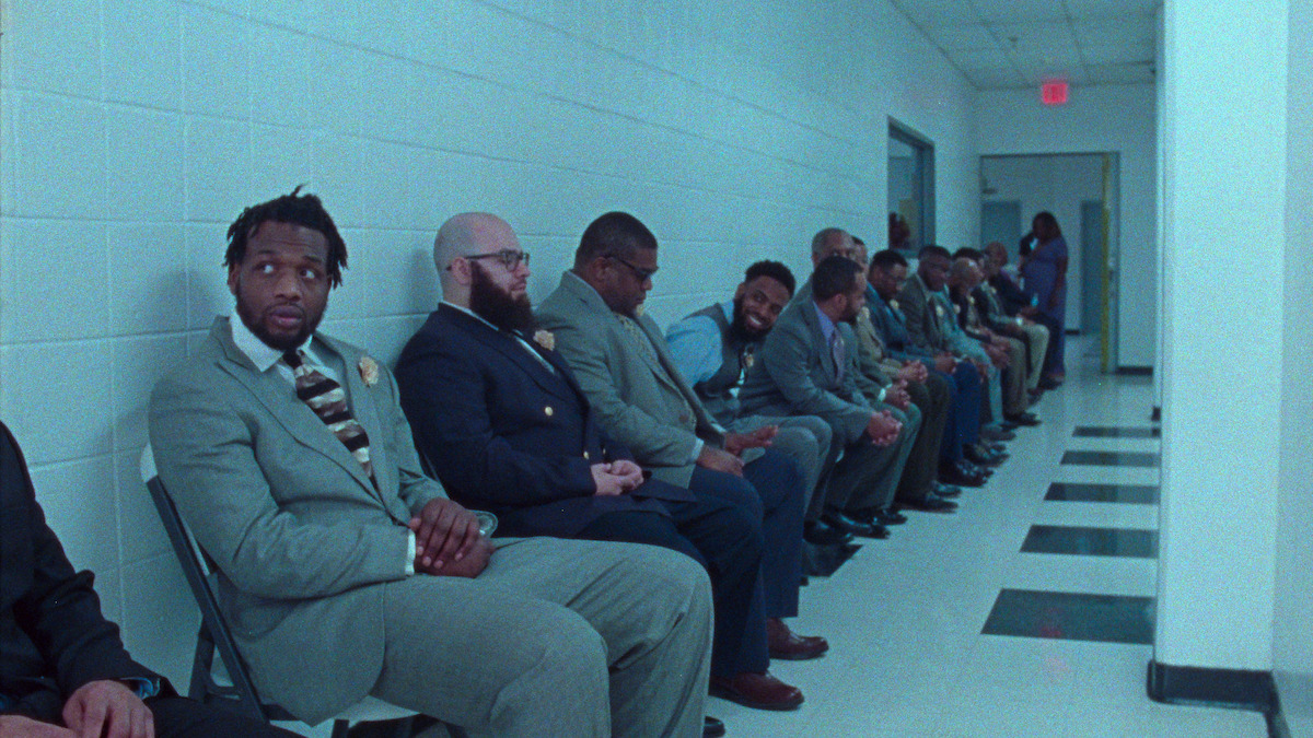 Dads anxiously await their daughters' arrivals, sitting in a line down a long hallway.
