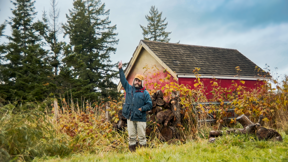 Zach Galifianakis stands in a field with one hand in the air in ‘This Is a Gardening Show.’