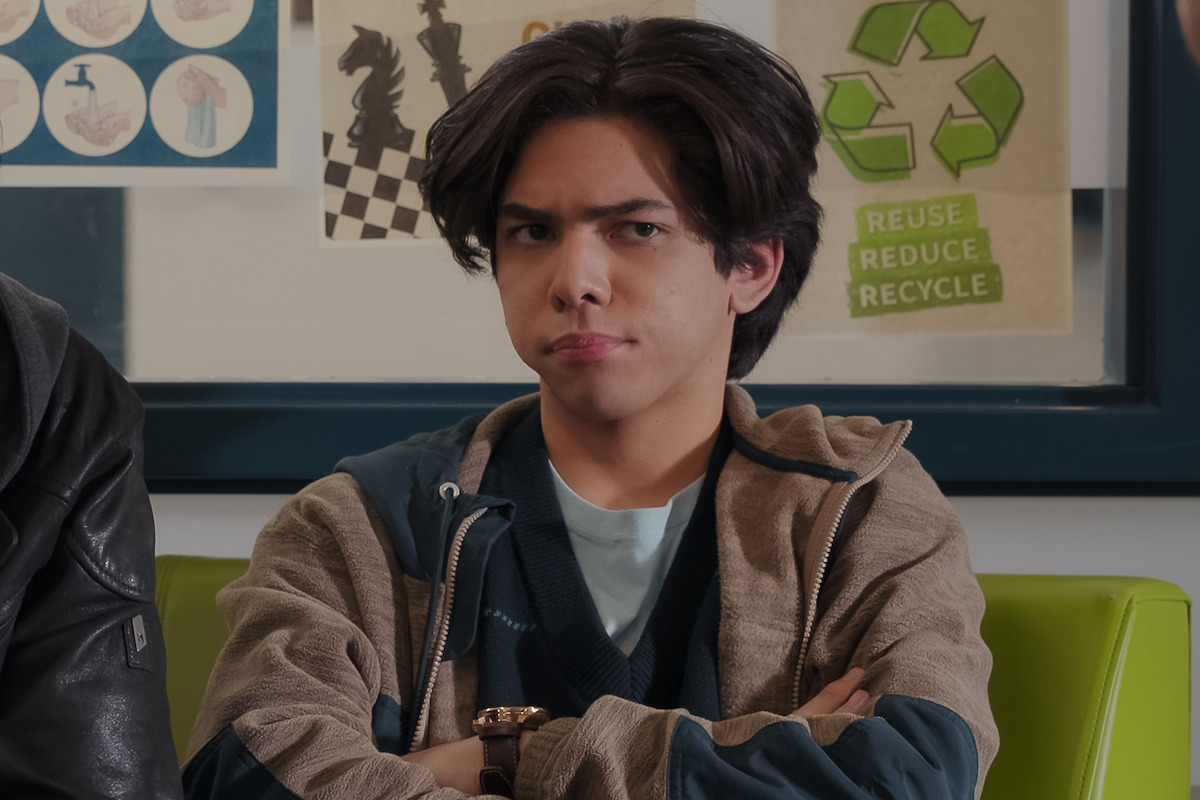 Myles Perez as Lee sits with his arms folded in ‘My Life with the Walter Boys’ Season 1.