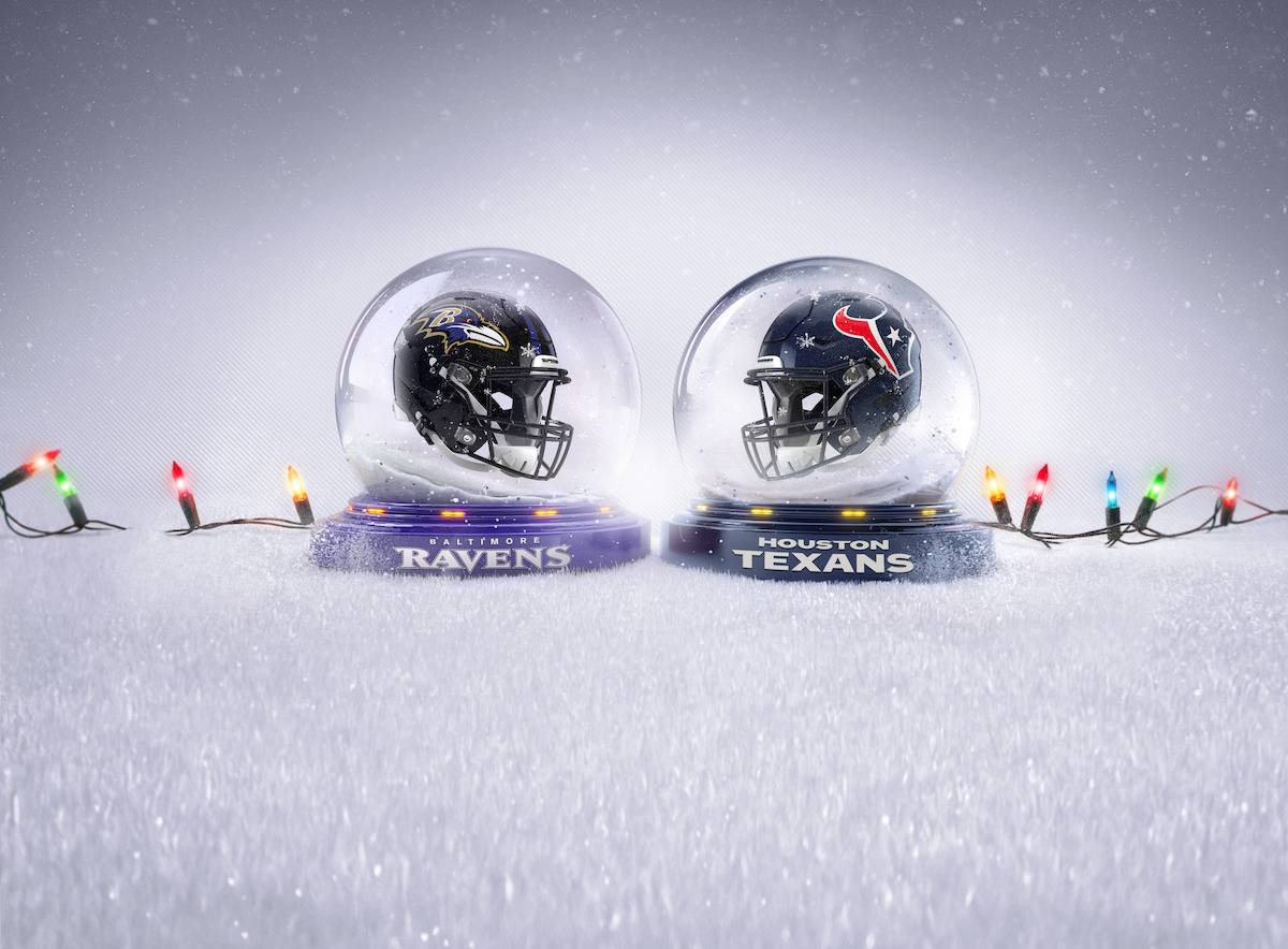 A Baltimore Ravens and Houston Texans helmet in snow globes surrounded by Christmas lights.