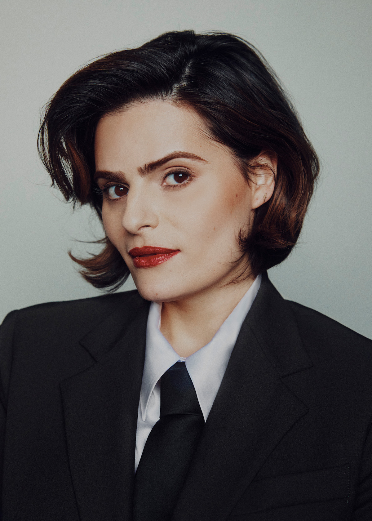 Nava Mau wears a suit, tie, and bowler hat.