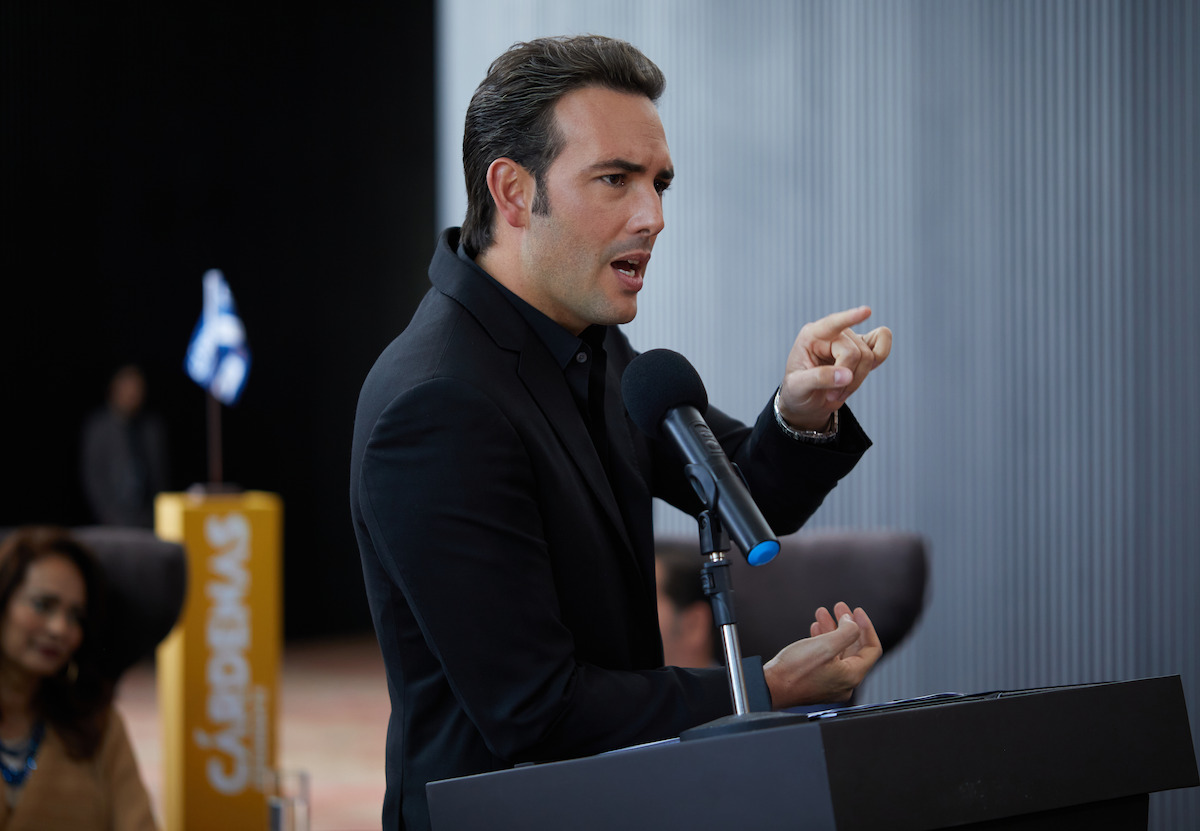 Man standing at podium wearing black suit