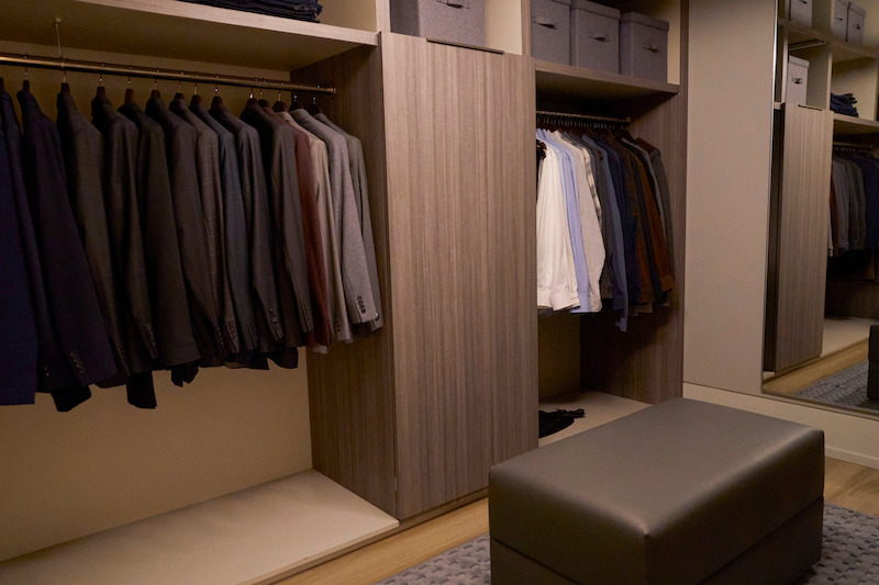 Walk-in closet full of neat, hanging clothes.