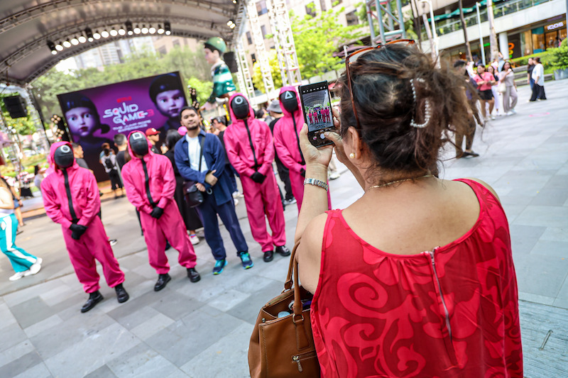 A fan poses for a photo with pink guards at a 'Squid Game' Season 3 event in Manila, Philippines.