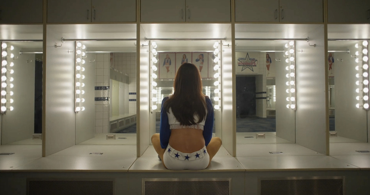 A Dallas Cowboys Cheerleader looking into a mirror.