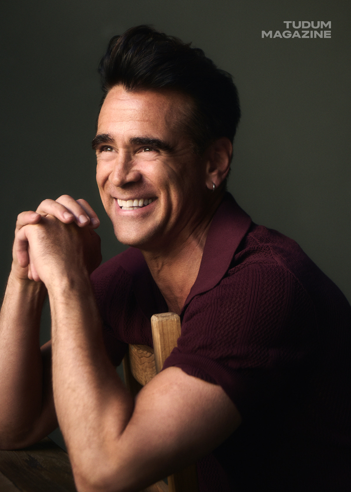 Colin Farrell smiles while wearing a maroon polo.
