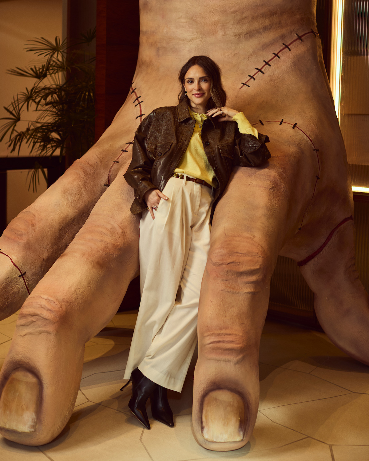 Atriz Isabelle Drummond posa em frente a uma escultura de mão na sede da Netflix