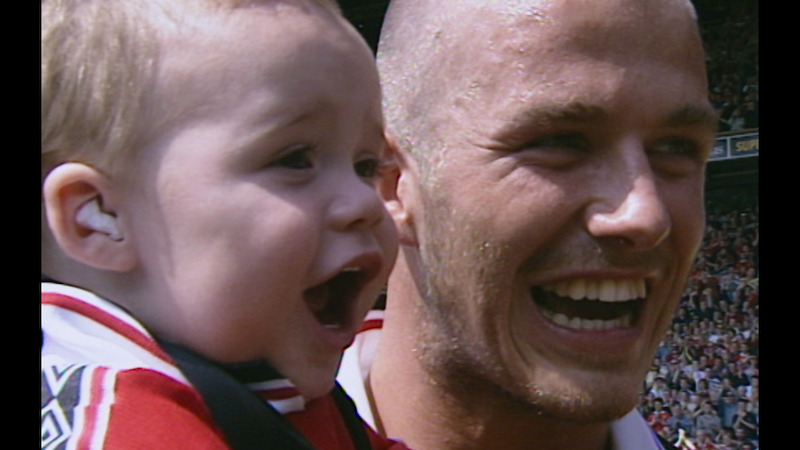 David Beckham holding his son at a match