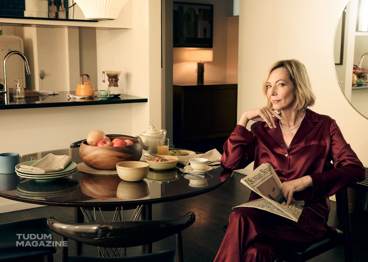 Allison Janey reads a newspaper at a kitchen table