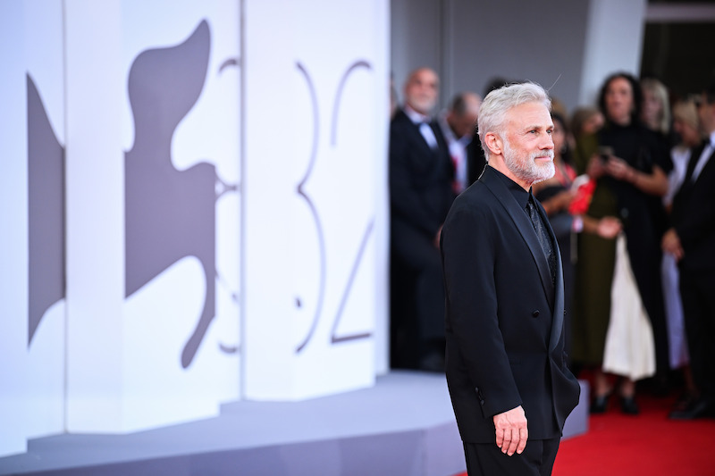 Christoph Waltz stands in a black outfit on the red carpet.