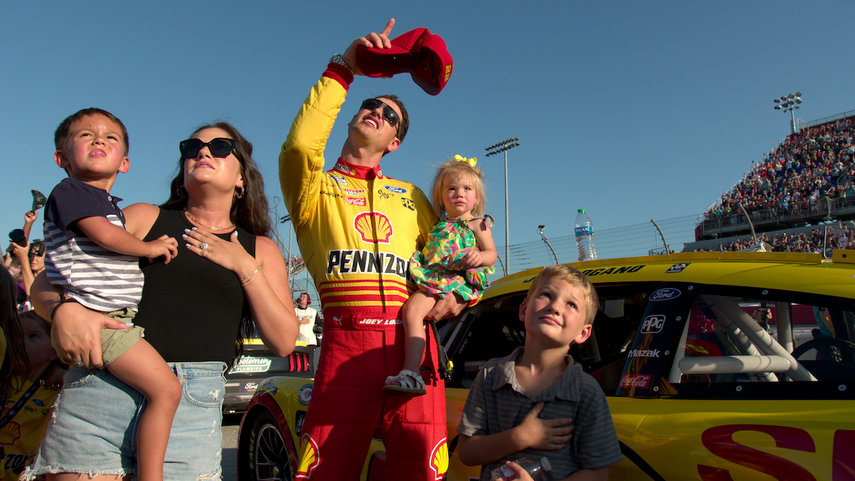 Joey Logano and family stand together on a race track in ‘NASCAR: Full Speed.’