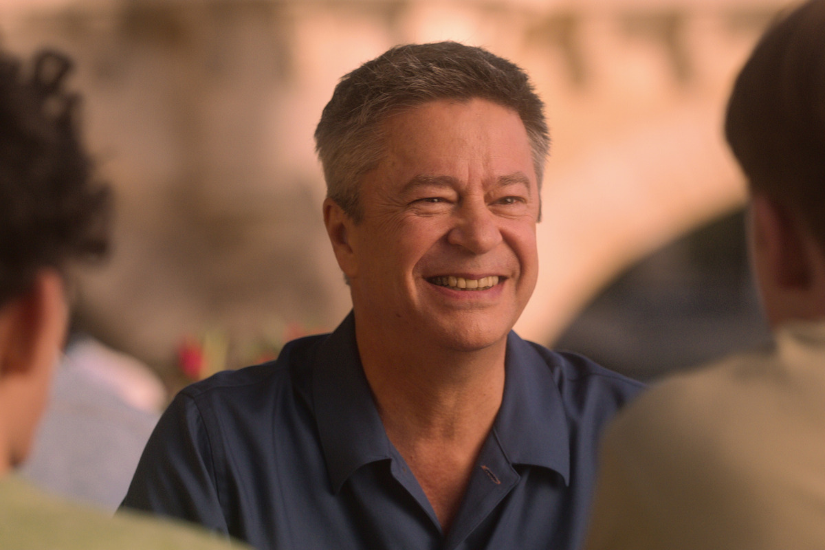 Thibault de Montalembert as Stephane sits at a cafe smiling in Season 2 of ‘Heartstopper.’