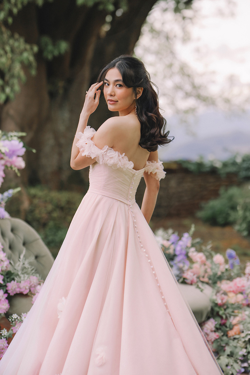 Woman in pink dress looks over her shoulder and smiles.