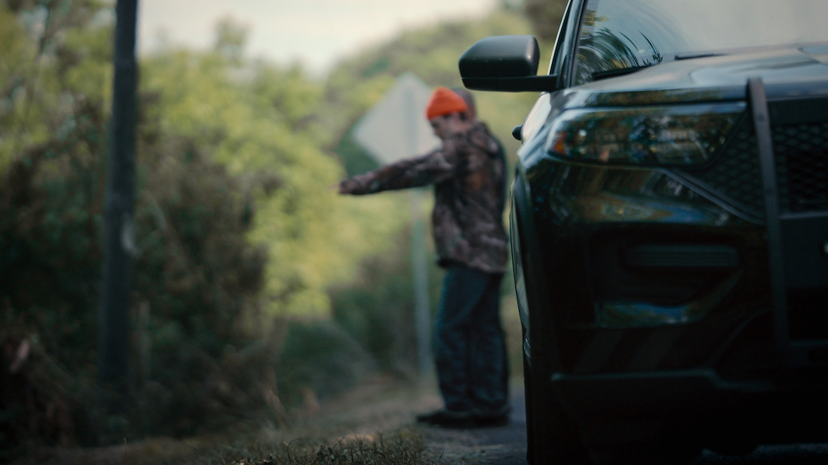 A boy standing on the side of a road points to where he found the head of Jane Doe.