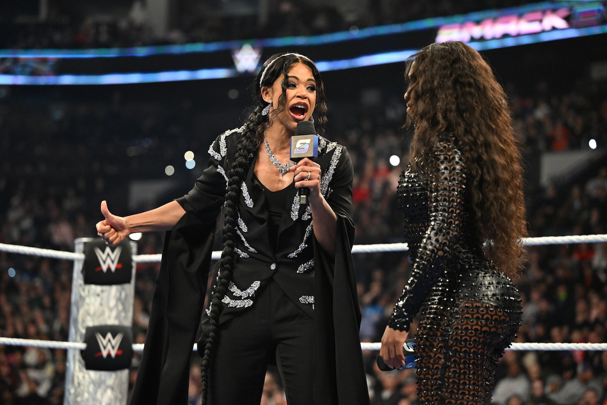 Bianca Belair yells into a microphone in the ring with Naomi.