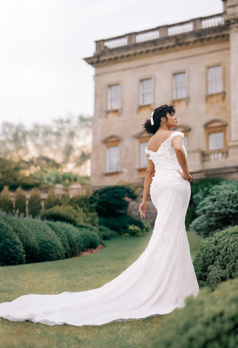 Woman in bridal dress poses with adorned building behind her.