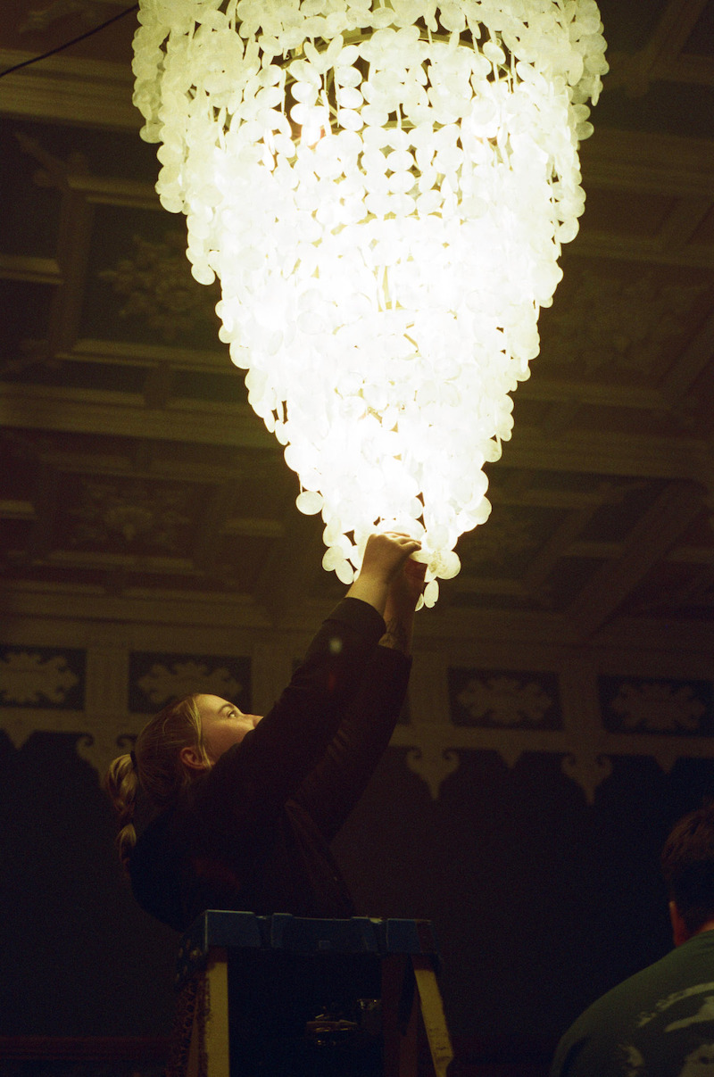 The crew adjusts a chandelier behind the scenes in season 1 of 'Fool Me Once' 