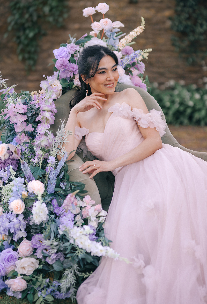 Woman in bridal dresses poses and looks off into the distance.