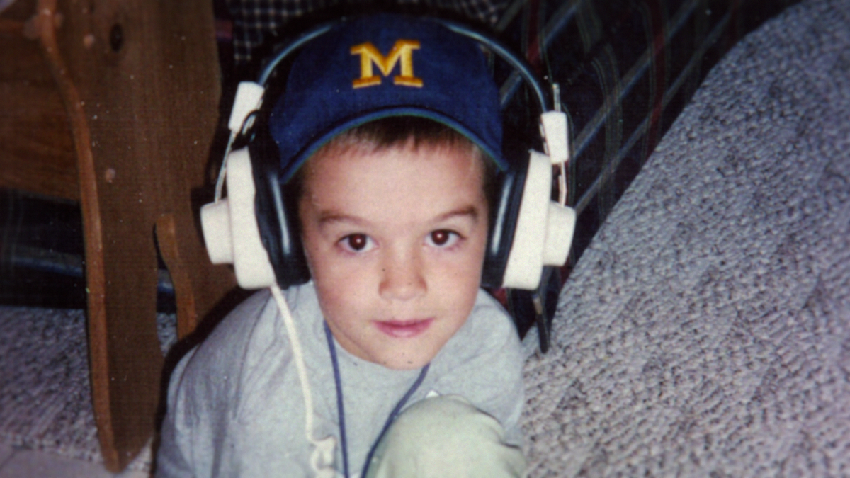 A young Connor Stalions wearing a headset and Michigan Wolverines hat.