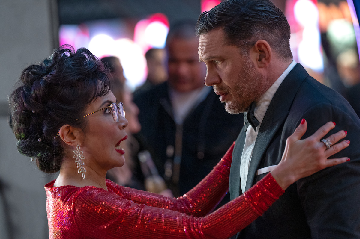 With a look of surprise on her face, Peggy Lu as Mrs. Chen, wearing a red-sequined outfit, embraces a tuxedo-clad Tom Hardy as Eddie in ‘Venom: The Last Dance.’
