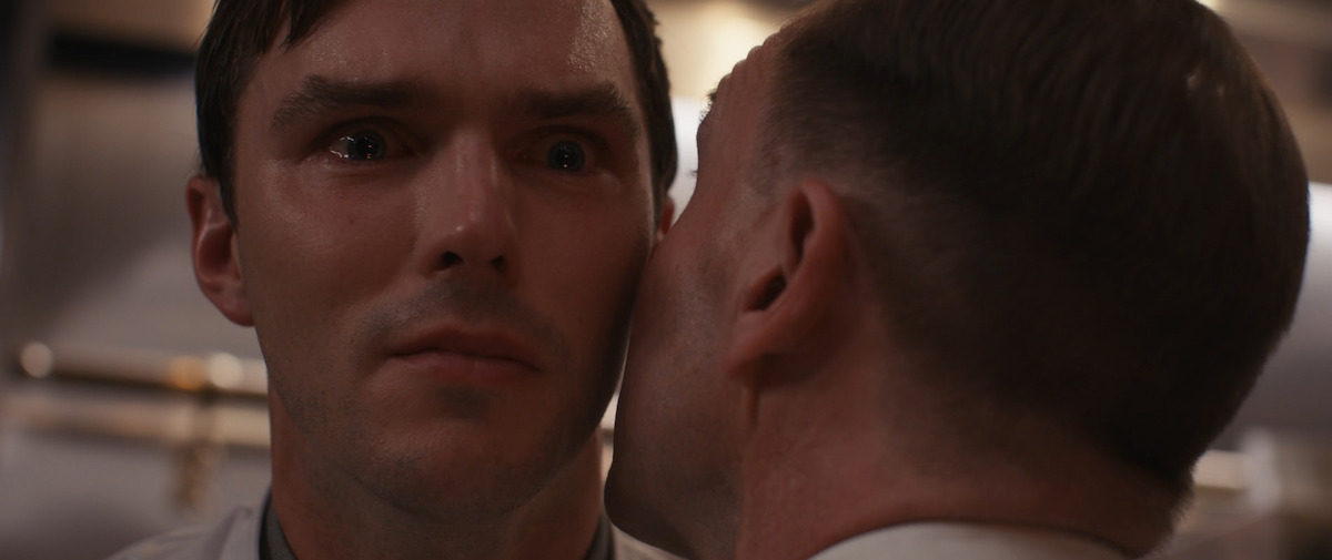 A man whispers in Nicholas Hoult’s ear in the film ‘The Menu.’