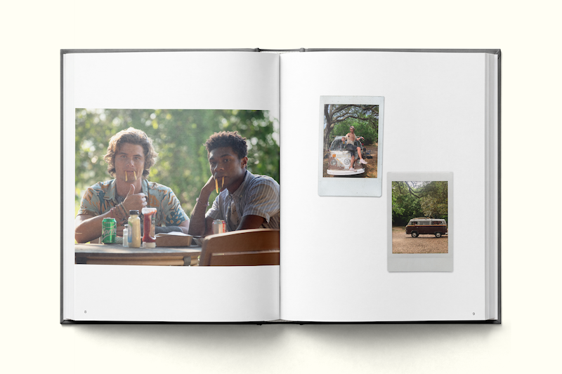 Photo book open to a page showing two friends drinking from soda cans outdoors at a picnic table, with trees in the background; two instant photos on the opposite page feature a barbecue scene and a parked van in a natural setting.