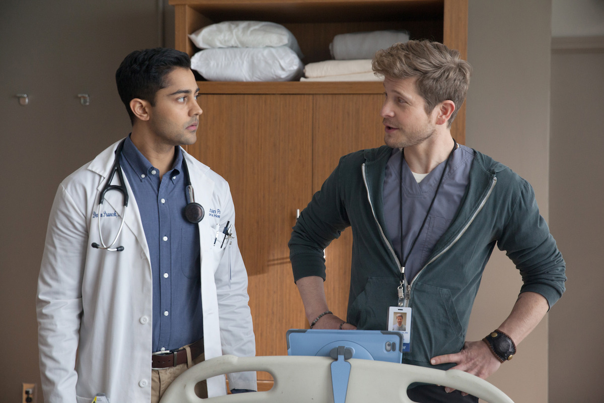 Manish Dayal as Devon Pravesh and Matt Czuchry as Conrad Hawkins stand in an exam room together in ‘The Resident.’