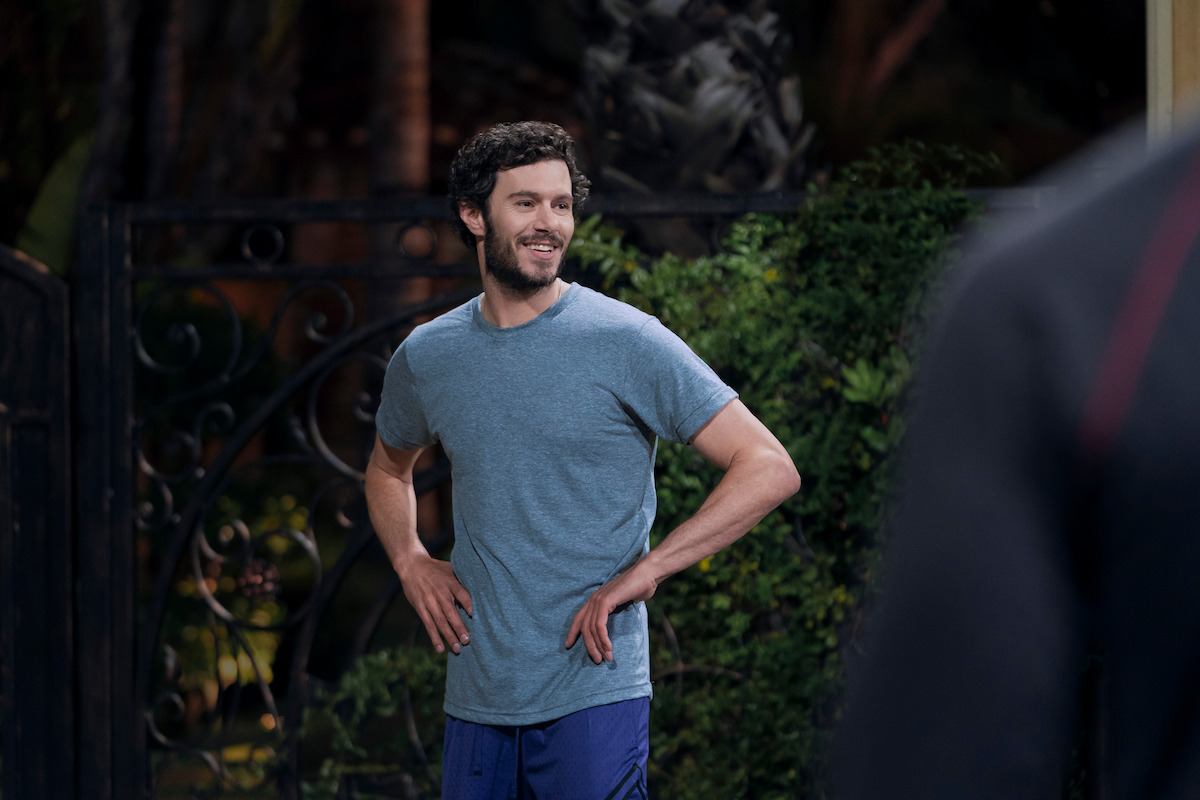 Noah (Adam Brody) wears a blue-grey t-shirt and blue shorts.
