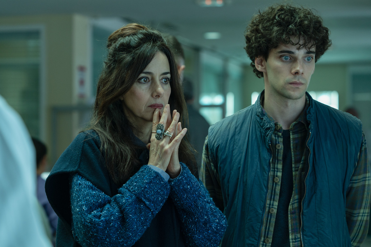 In an image from the series ‘The Gardener,’ Cecilia Suárez as La China Jurado clasps her hands together as if in prayer while standing next to Álvaro Rico as Elmer as the two stand side-by-side looking shocked.