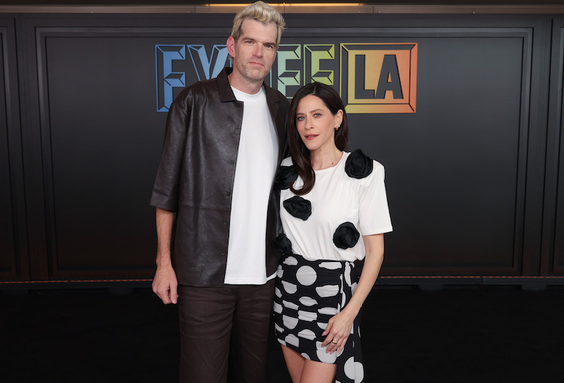 Two people pose in front of a backdrop that says FYSEE.