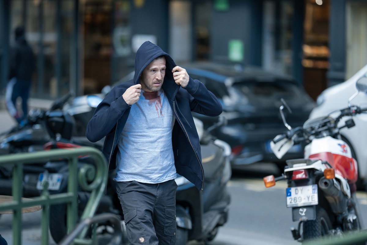Guillaume Canet as Franck pulls his hood over his head as he walks through the streets in the film ‘Ad Vitam.’