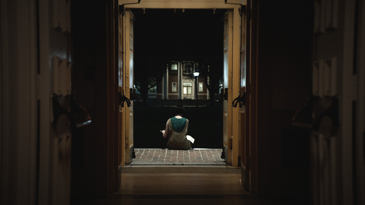 A girl sits on the entry steps of a building.