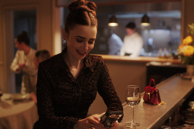 Lily Collins as Emily smiles at a bar in Season 4 of 'Emily in Paris'
