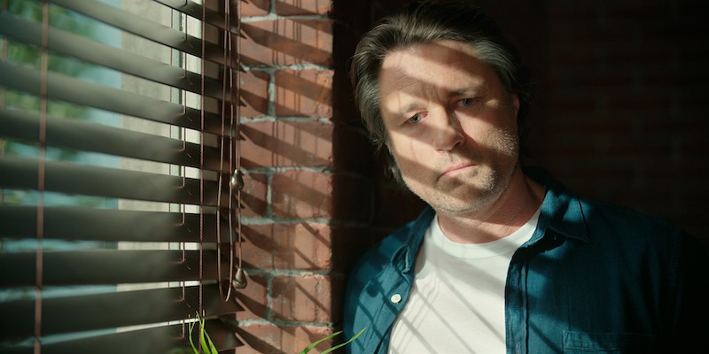 Martin Henderson as Jack Sheridan standing in front of a window.