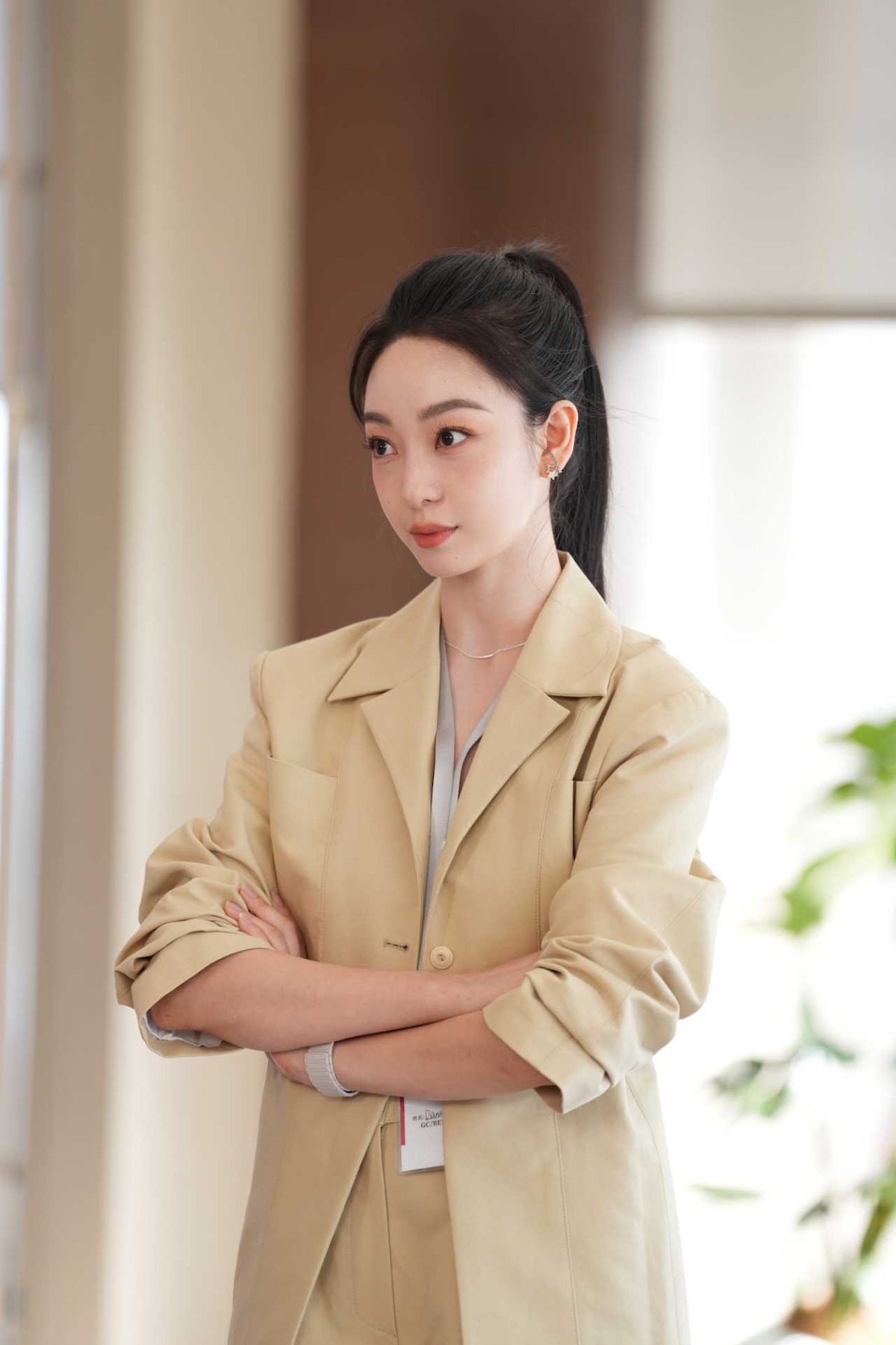 Mulher asiática de blazer cruza os braços