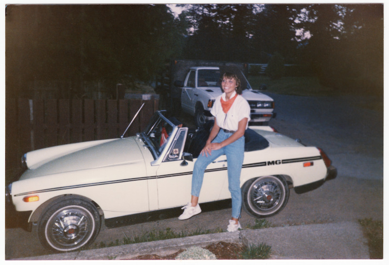 Pamela sitting on a white convertible.